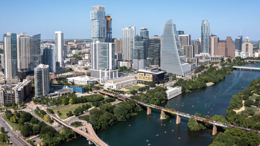 A skyline view of Austin, TX with Lady Bird Lake and multiple overpasses in the frame.