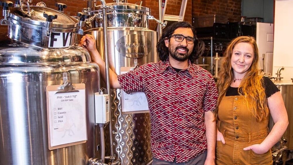 Owners Wendy + Felipe stand in front of the brew kettles.