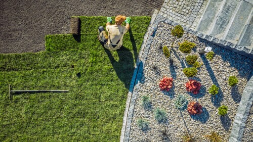 an aerial view of a landscaper laying down turf