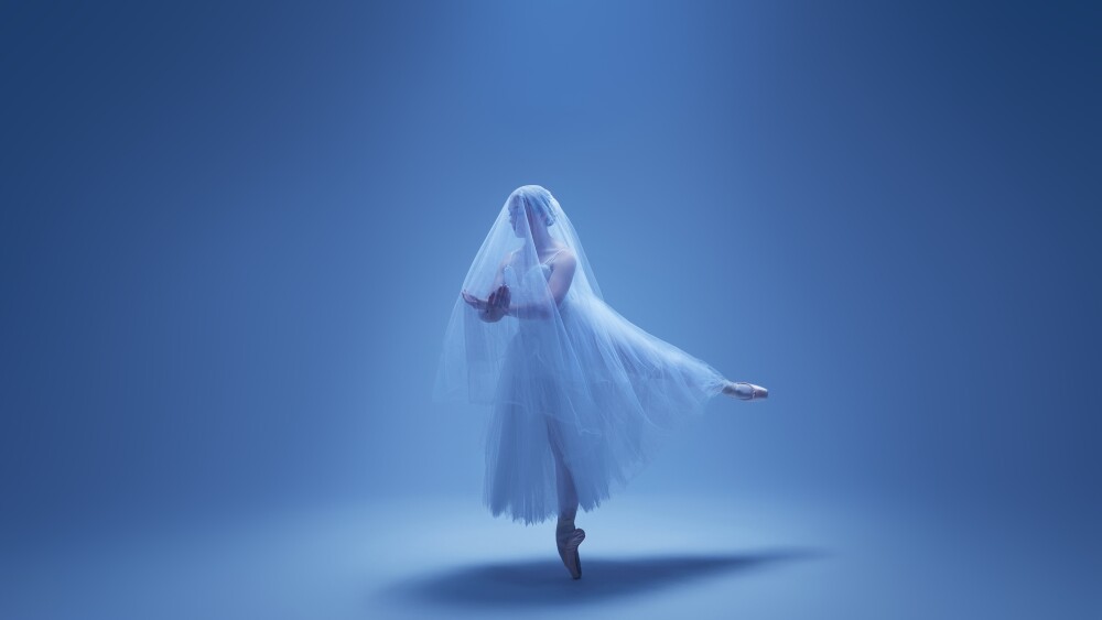 studio portrait of a ballet dancer in front of a blue backdrop