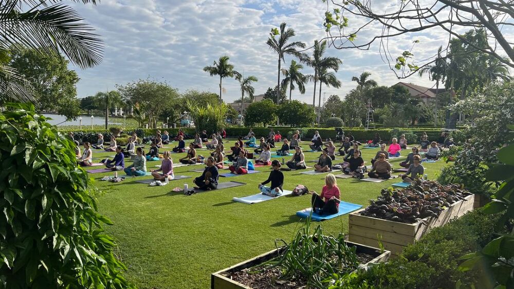 A group of people sit on yoga mats doing a yoga practice in Hollis Garden in Lakeland, FL