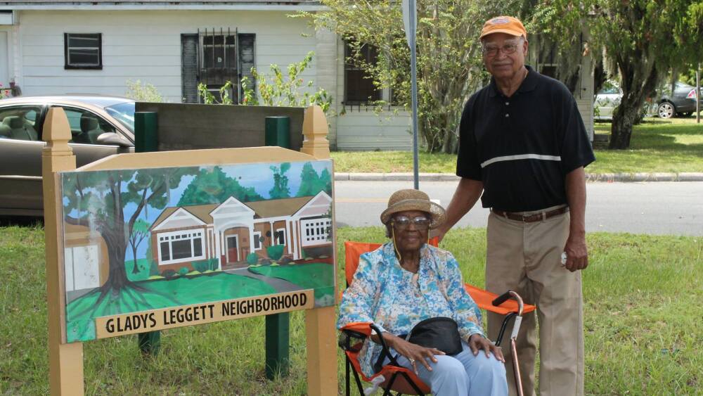 Gladys Leggett and neighborhood president Morris Chestang pose next to the neighborhood's sign