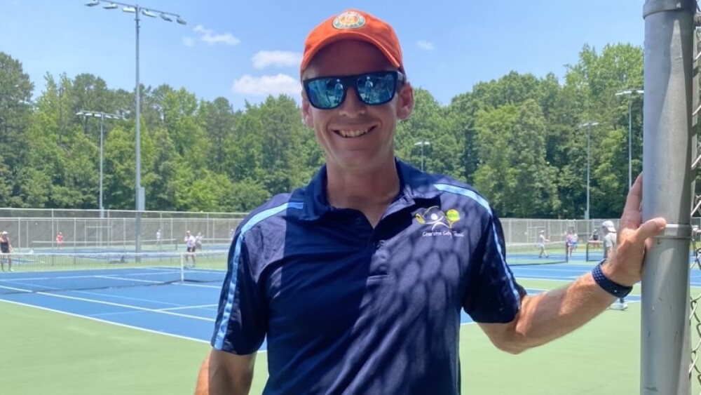 Charlotte City Tennis coach Bradley Hunt smiles for the camera.