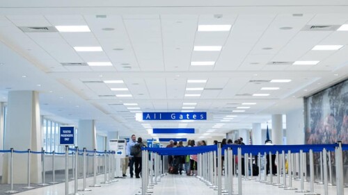 Rows of blue line barriers leading up to the all gates sign inside the airport