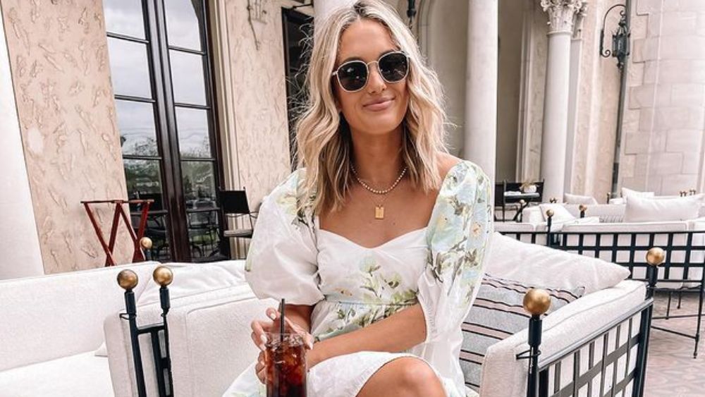 Austin-based influencer, Emily Travis, poses on a restaurant patio with an iced beverage in Austin, Texas.