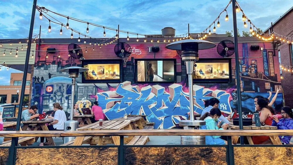 A colorful mural on a patio with string lights.