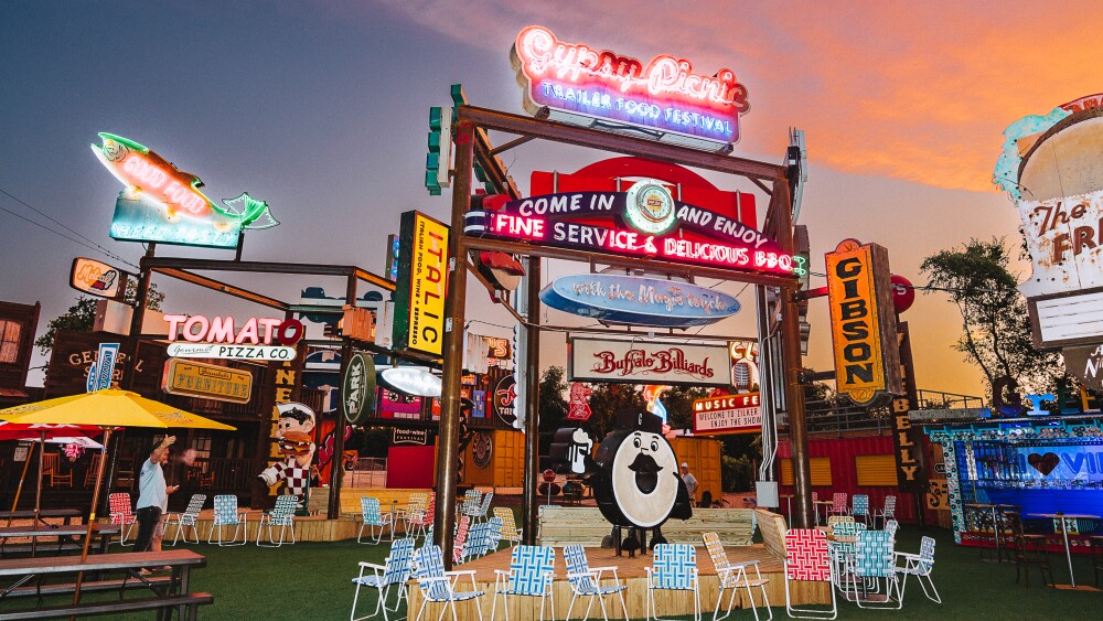 Dozens of signs, some glowing, at an outdoor space with folding chairs in the foreground.