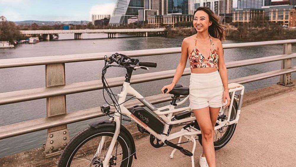 Koko, an Austin-based influencer and blogger, poses with an eBike with Austin's skyline in the background.