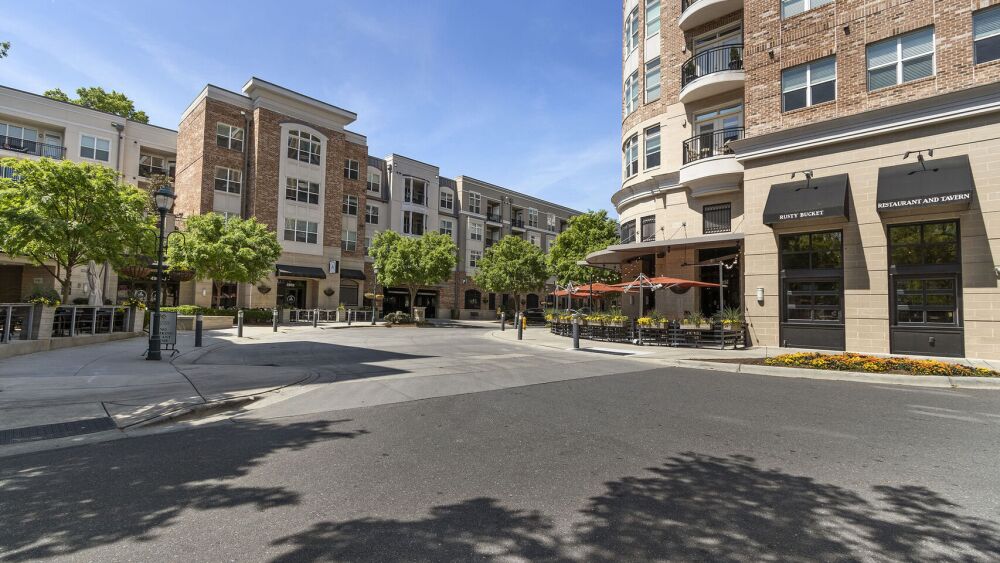 An exterior photo of a street and mixed-use building with retail on the bottom and three floors of apartments on the top.