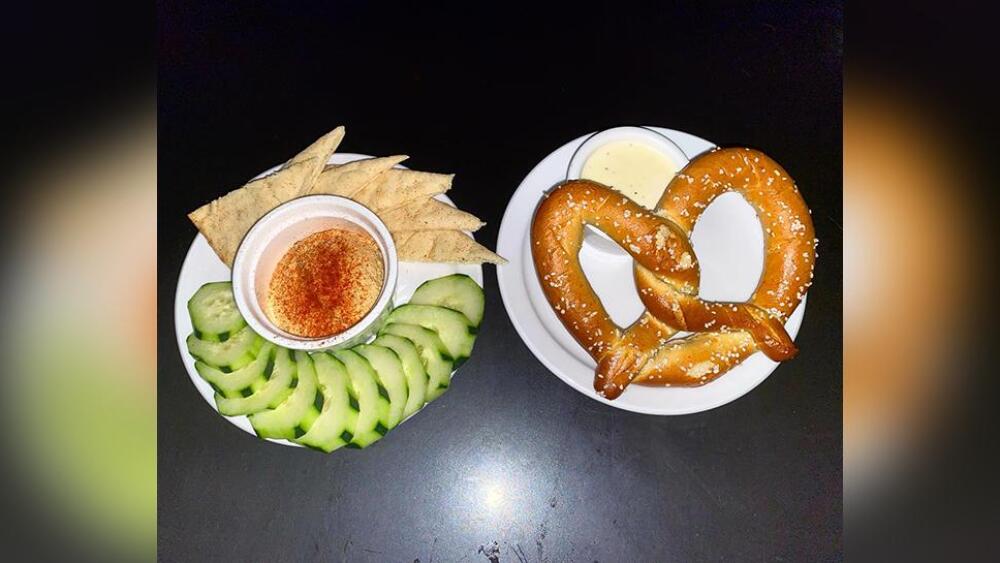 Plates of hummus with pita and cucumbers, and an oven-baked soft pretzel with dip at Aalto Lounge in Portland, Oregon.