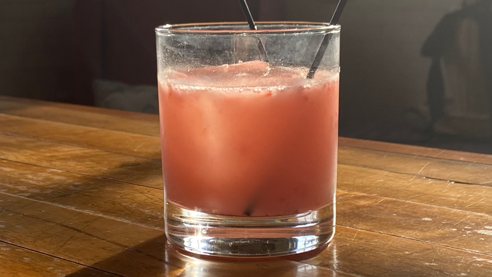 Pink drink in a cocktail glass on a wooden bar.