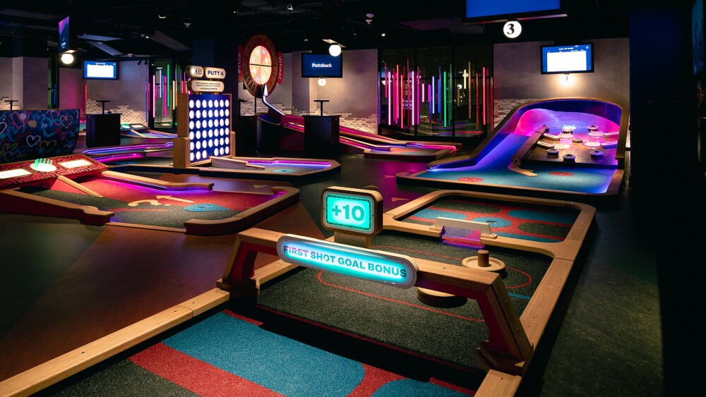 Indoor mini-gold course with neon lights.