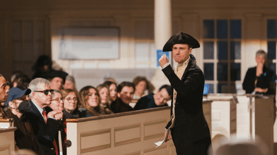 A man dressed in colonial clothing makes a fist during the Boston Tea Party reenactment at the Old South Meeting House.