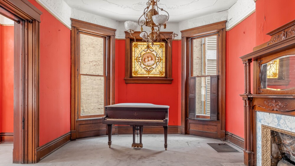A stained glass window sits over a piano in a mansion that dates to at least 1903.