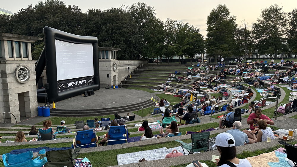 People sit on blankets and folding chairs in Bicentennial Capitol Mall State Park in front of the Nightlight 615 outdoor movie screen.