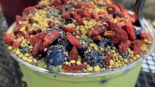 A green smoothie bowl with blueberries, goji berries, and bee pollen