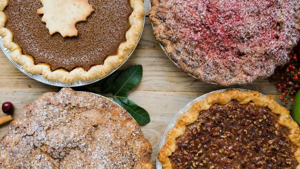 Overhead view of four different Thanksgiving holiday pies on table from Bakery Lorraine