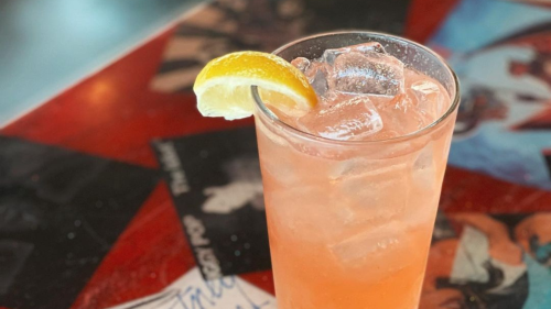 A pink soda cocktail sits on a bar.