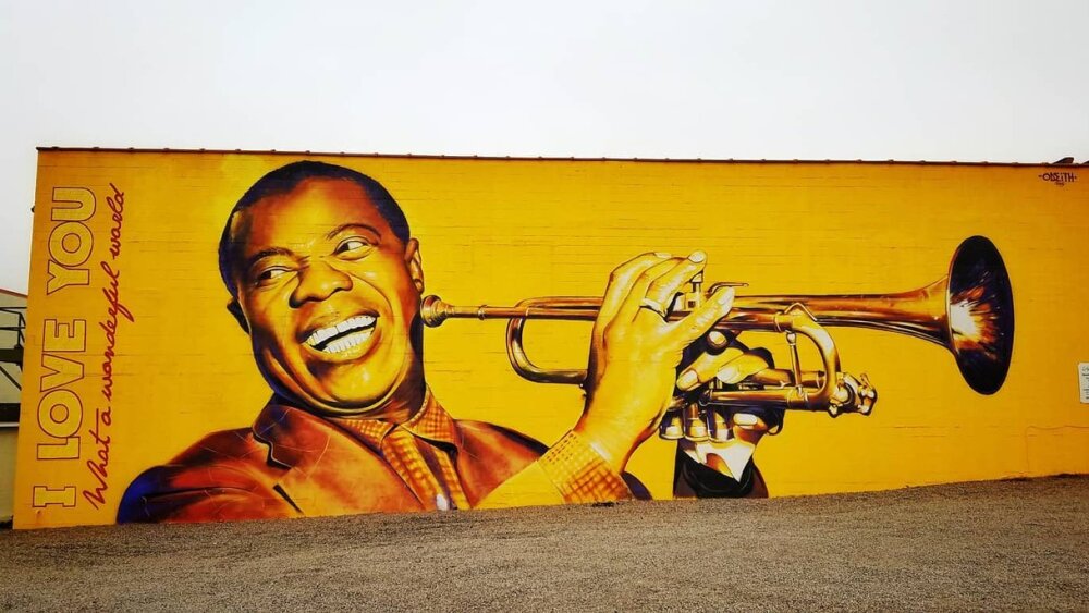 A yellow and gold mural of Louis Armstrong and a trumpet