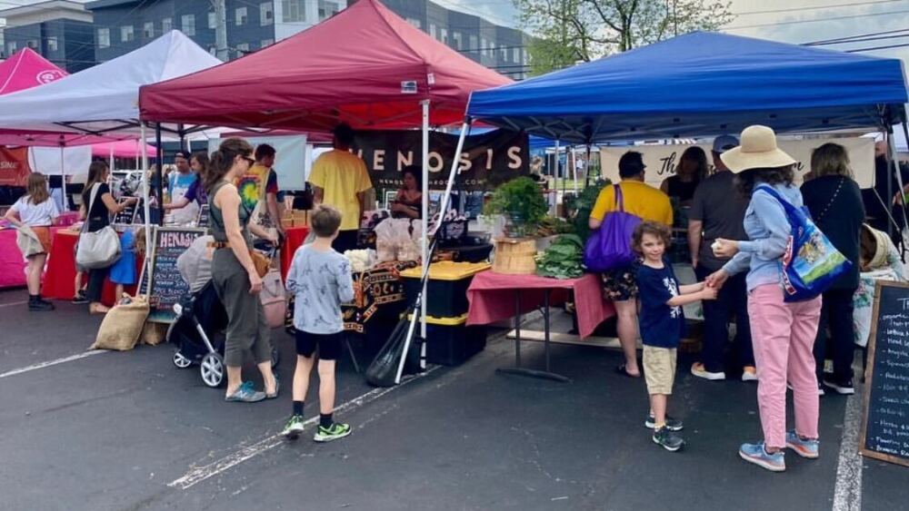 Farmers market shoppers stop inside tents to look at vendors' products at the East Nashville Farmers Market.