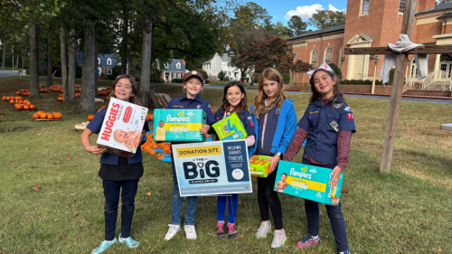 An image of young children holding up boxes of diapers.