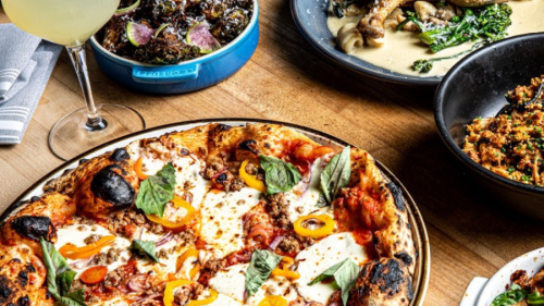Numerous plates of Italian dishes are lined on a table.