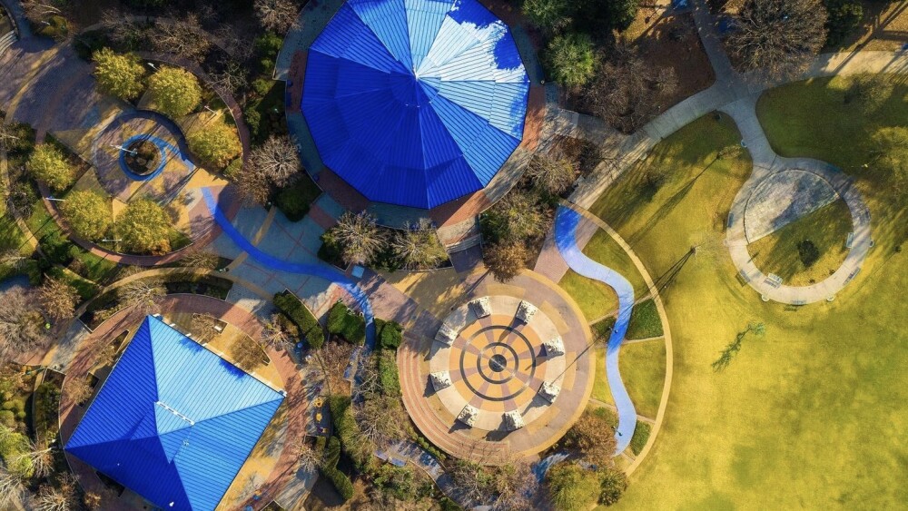 Aerial photo of Coolidge Park showing the bright blue roofs of the facilities and the fountains next to green grass. 