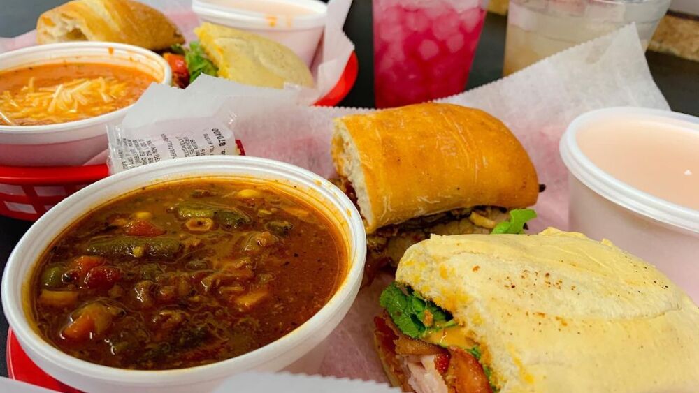 A table filled with sandwiches and bowls of soup.