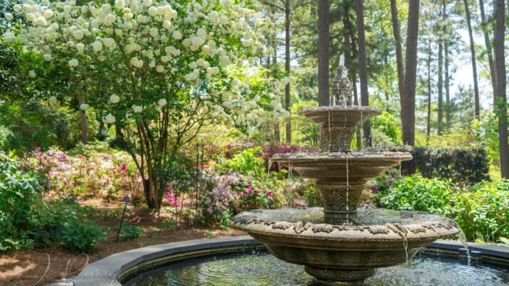 A garden with flowers and trees and a fountain