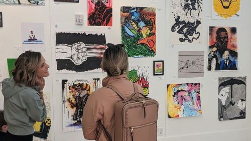 Two women standing in front of a wall of art at the LASC.