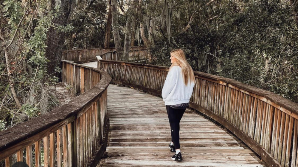 Woman walking a trail through trees.