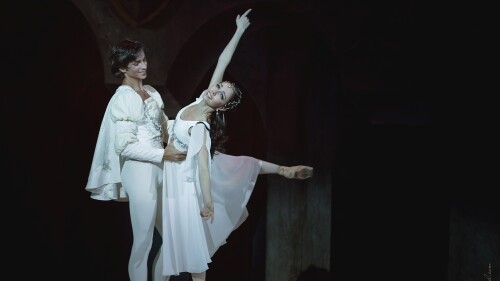Kateryna Kukhar and Oleksandr Stoianov perform a ballet duet on stage in white costumes.