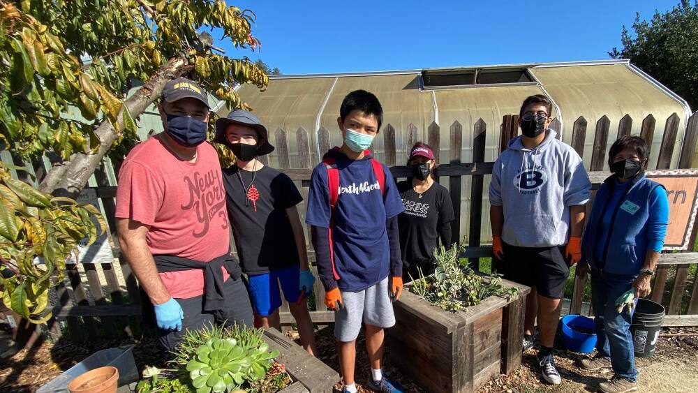 A group of volunteers standing next to planter boxes.