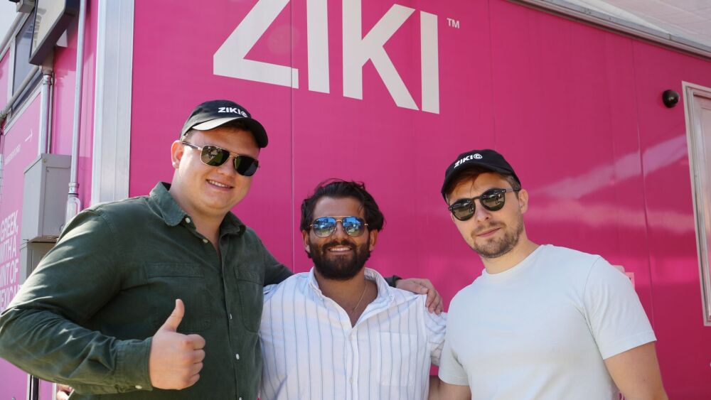 Three men stand in front of a food truck giving "thumbs up" with their arms around each other.