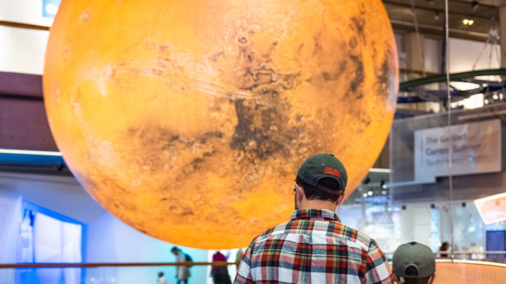 Two people standing in front of the Mars globe at the Museum of Science.