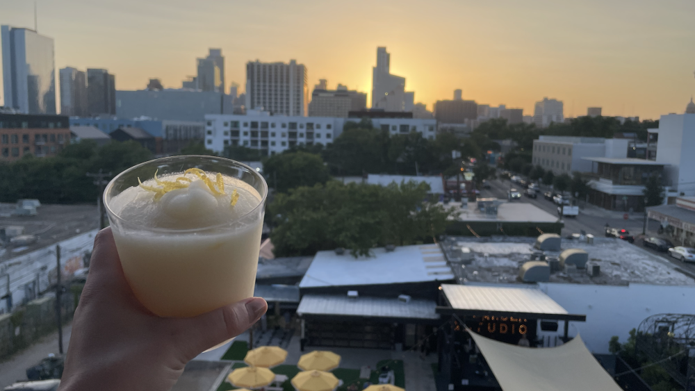 A piña colada in the foreground with the Austin skyline in the background.