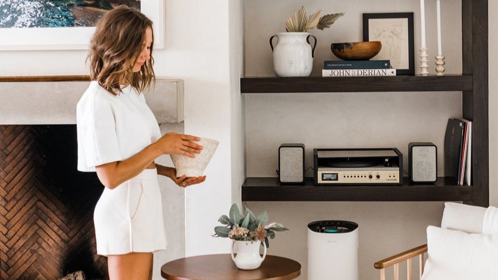 Austin-based lifestyle blogger and influencer Camille Styles poses in her home with an air purifier.