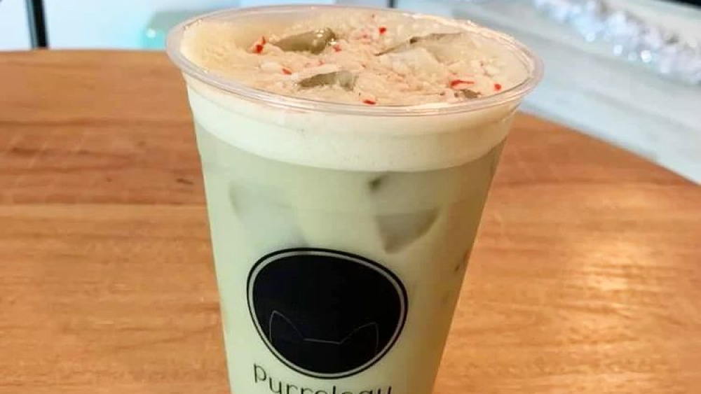 A peppermint matcha iced latte topped with crushed candy canes