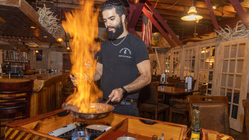A chef at Kafe Kokopelli in Dade City flambés a dish tableside, creating a dramatic fire display in the rustic-themed restaurant.