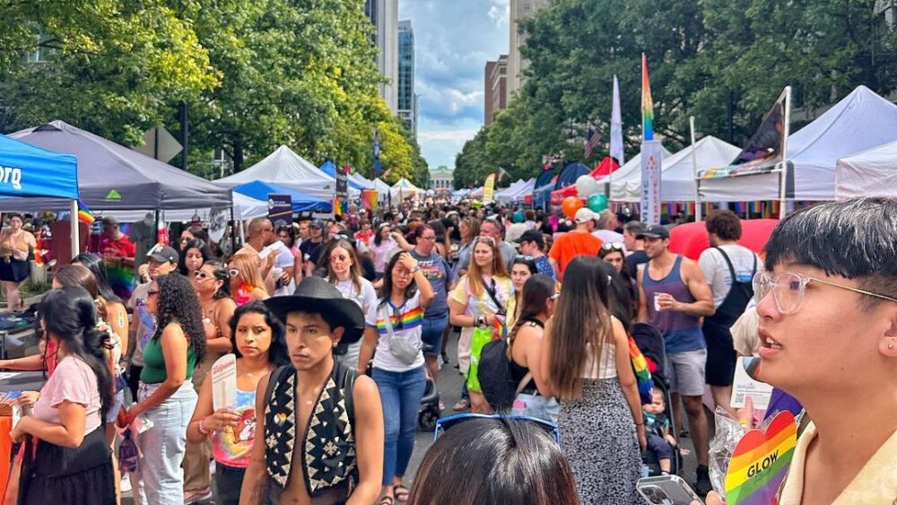 A crowd of people and booths celebrating Pride. 