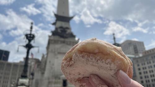 A donut held up in front of Monument Circle