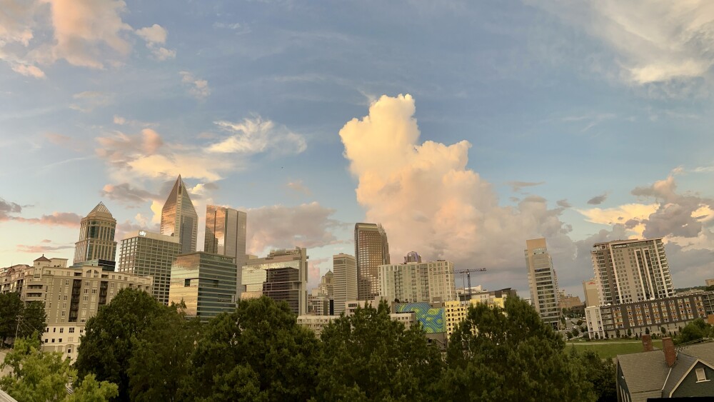 The Uptown Charlotte skyline with clouds in the sky in early evening.