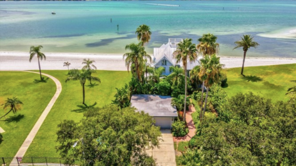 A home with lots of green space surrounding it and a view of the ocean in front.
