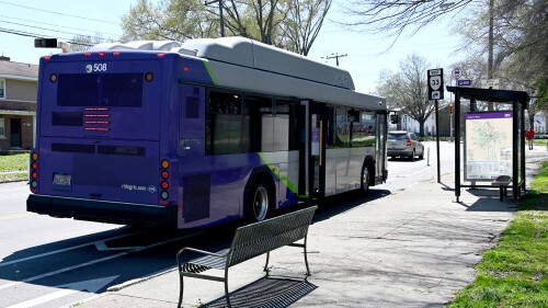 A GRTC bus at a stop with a small shelter and bench.