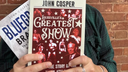 Hands are holding two books about wrestling.