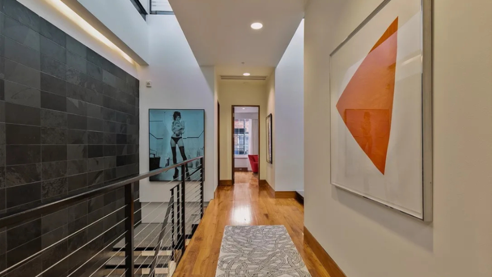 A hallway with a left-side stairwall; three art frames hang along the walls.