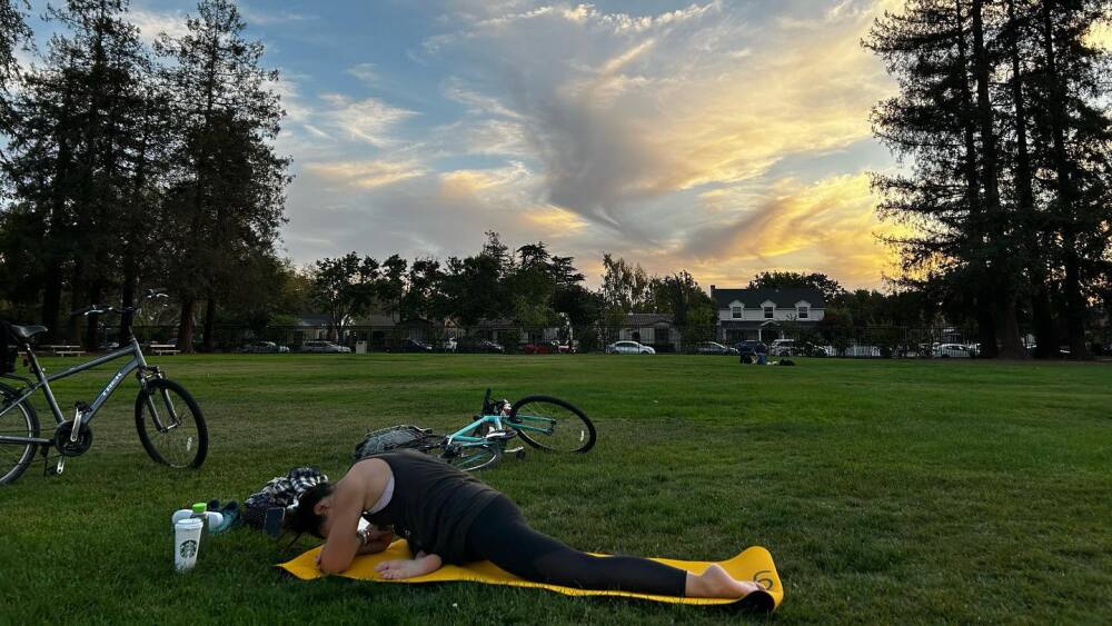 A woman in a yoga pose with the sunset in the background at the Municipal Rose Garden.