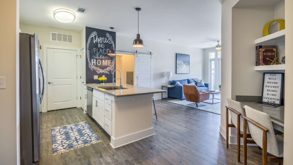 An interior of an apartment with a kitchen on the left and a seating area on the right.