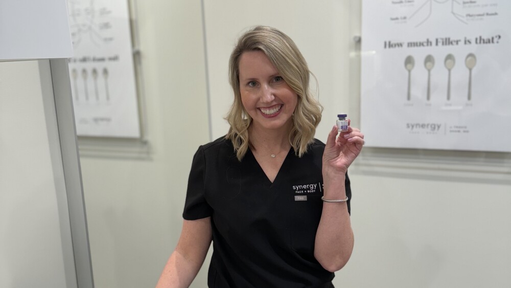 A person in a medical room holding a small clear vial.