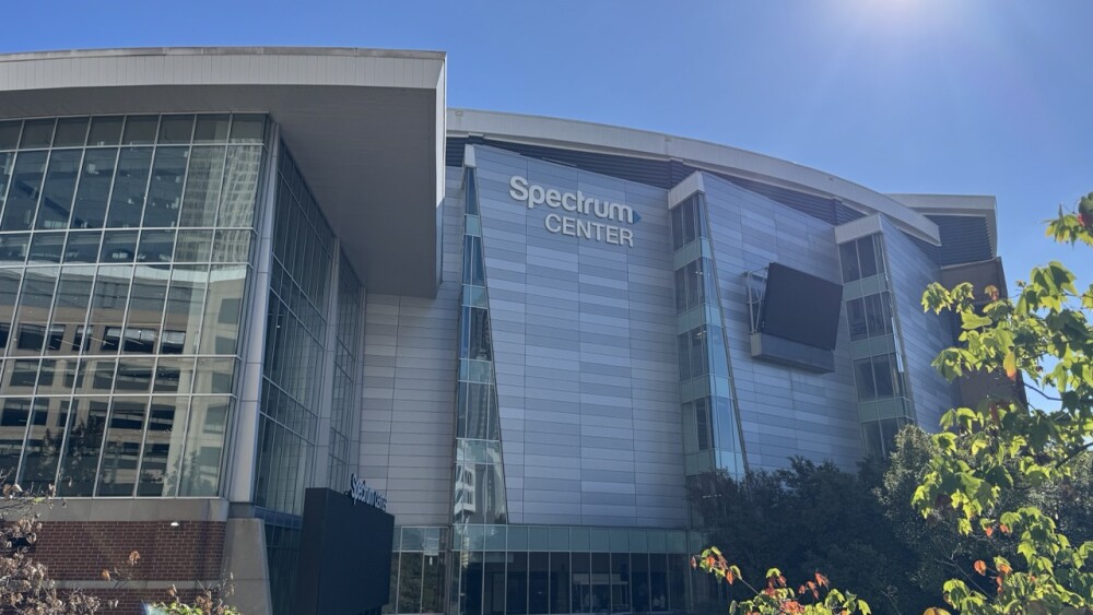 The sun shining above the exterior of the Spectrum Center.